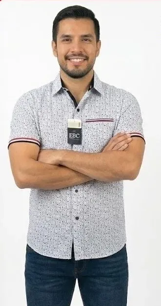 Camisa de vestir blanca con estampado de puntos pequeños, cuello camisero y manga corta con detalle en el borde.