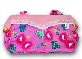 Pañalera de tela rosa con estampado de elefantes y globos, detallada con encaje blanco y un moño central decorativo.